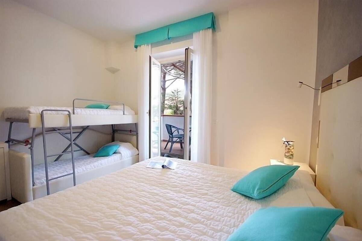 Une chambre avec un lit superposé, un lit simple et une petite table avec une lampe.