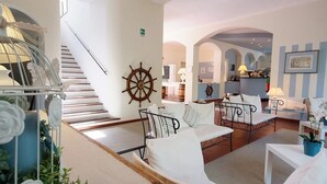 A hotel lobby with a staircase, seating area, and a bar. - Hotel Brigantino (Marciana)