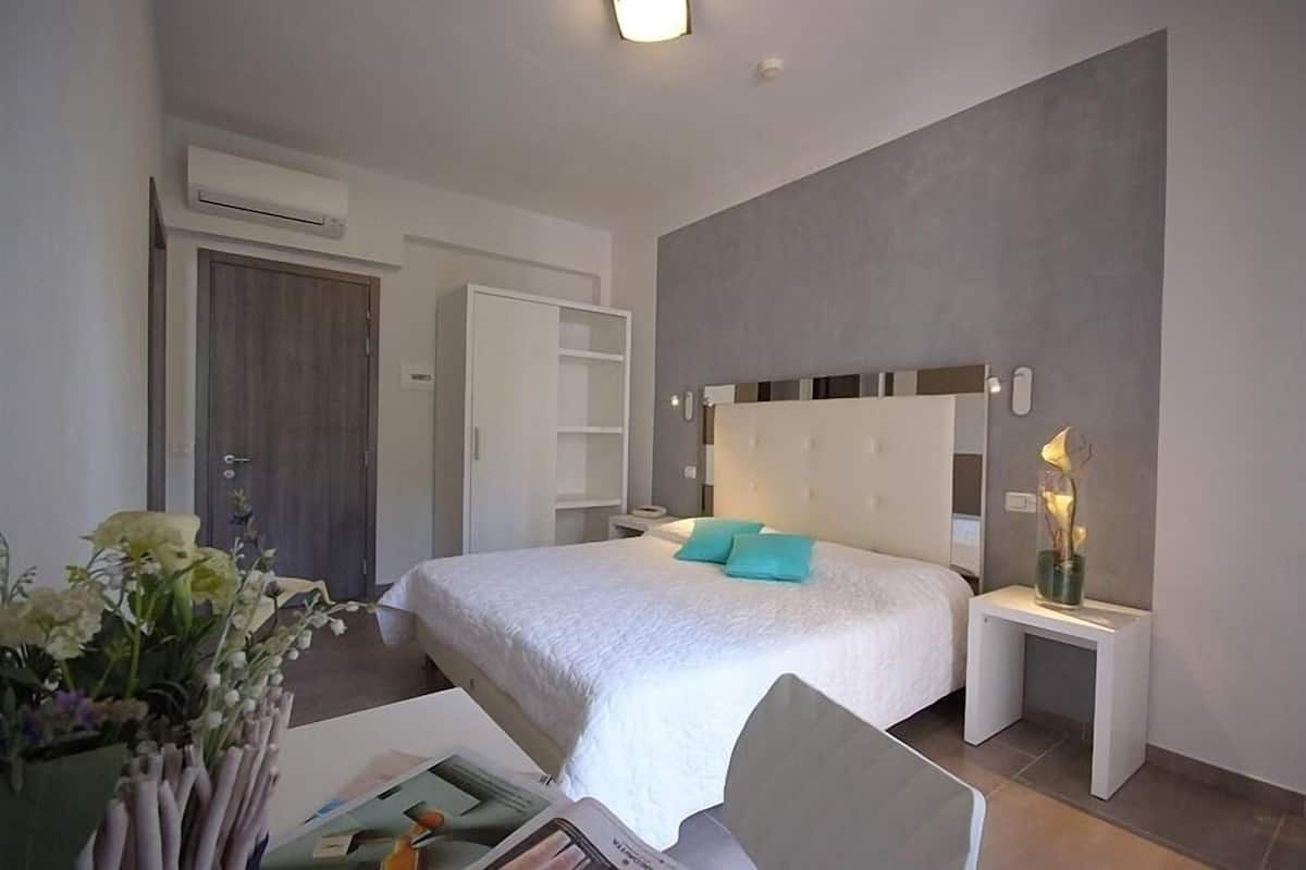 Une chambre d’hôtel moderne équipée d’un grand lit, de tables de chevet, d’une armoire et d’un appareil de climatisation.