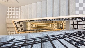 Un escalier moderne avec une rampe en métal et un mur orné de motifs.