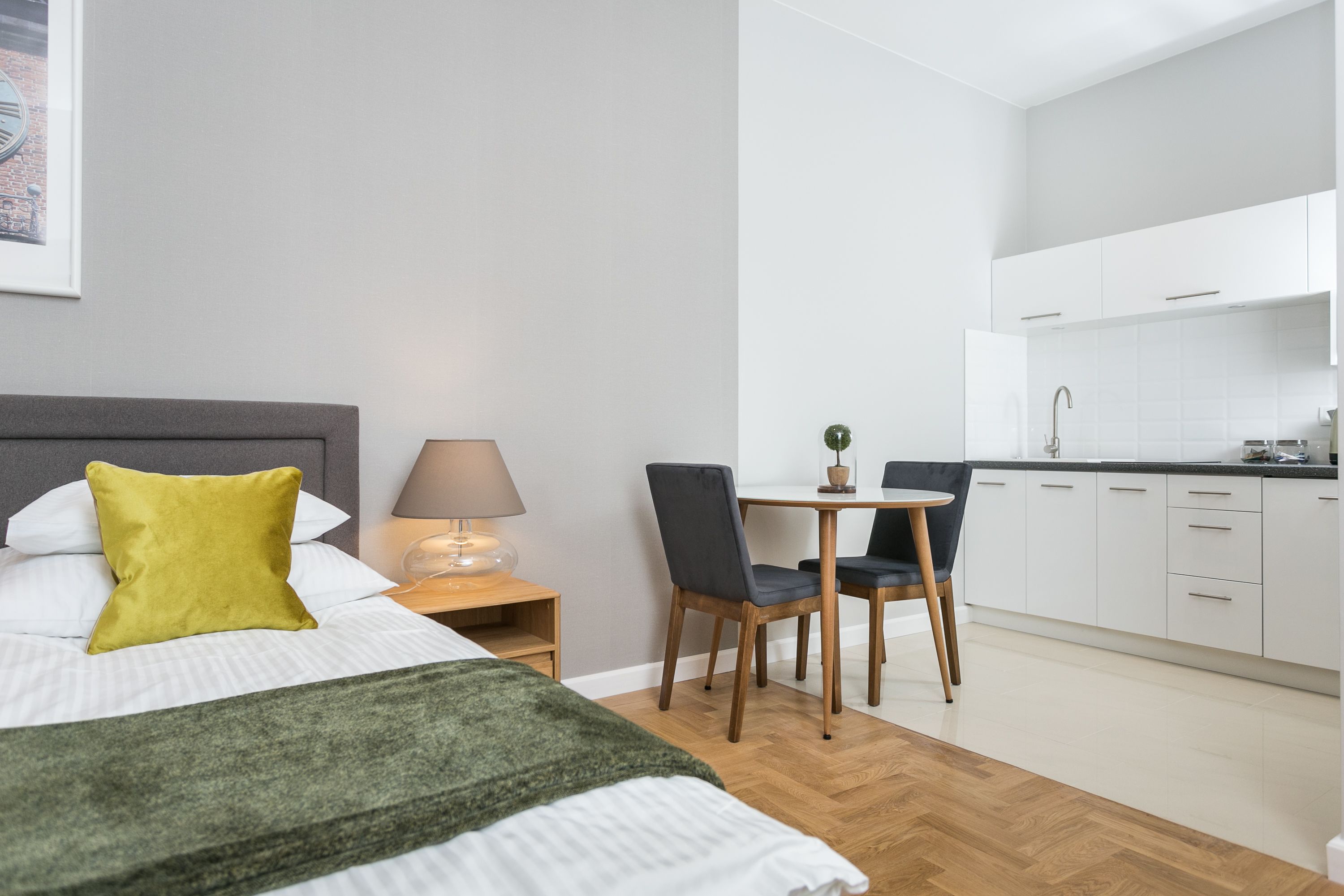 Een moderne hotelkamer met een bed, een bureau en een kitchenette.