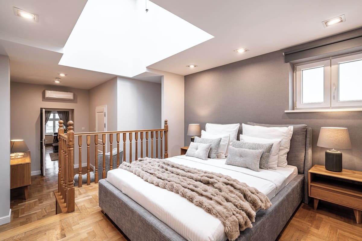 Un dormitorio moderno con una cama grande, cabecera de madera y tragaluz.