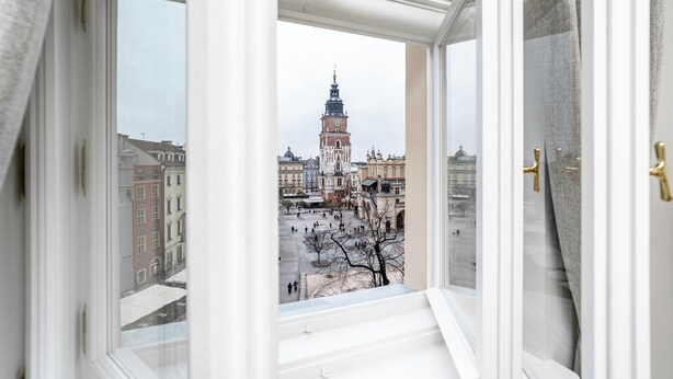 Une vue depuis une fenêtre donnant sur un paysage urbain, avec une tour imposante en évidence.