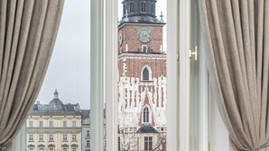 Une chambre avec une fenêtre donnant sur un bâtiment historique doté d’une tour avec une horloge.