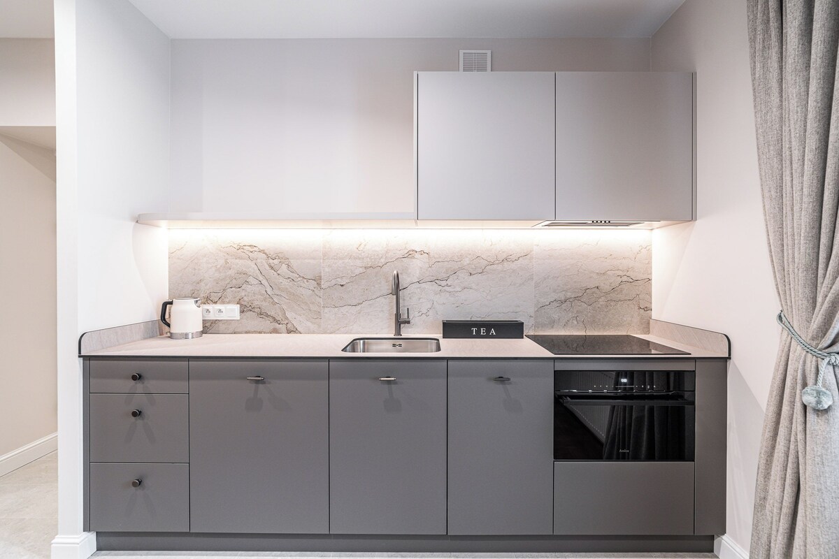 Een moderne keuken met een marmeren spatwand, een inbouwspoelbak en een theeset.