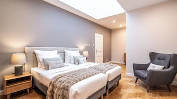 Un dormitorio moderno con una cama grande, dos mesitas de noche, una silla y un tragaluz.