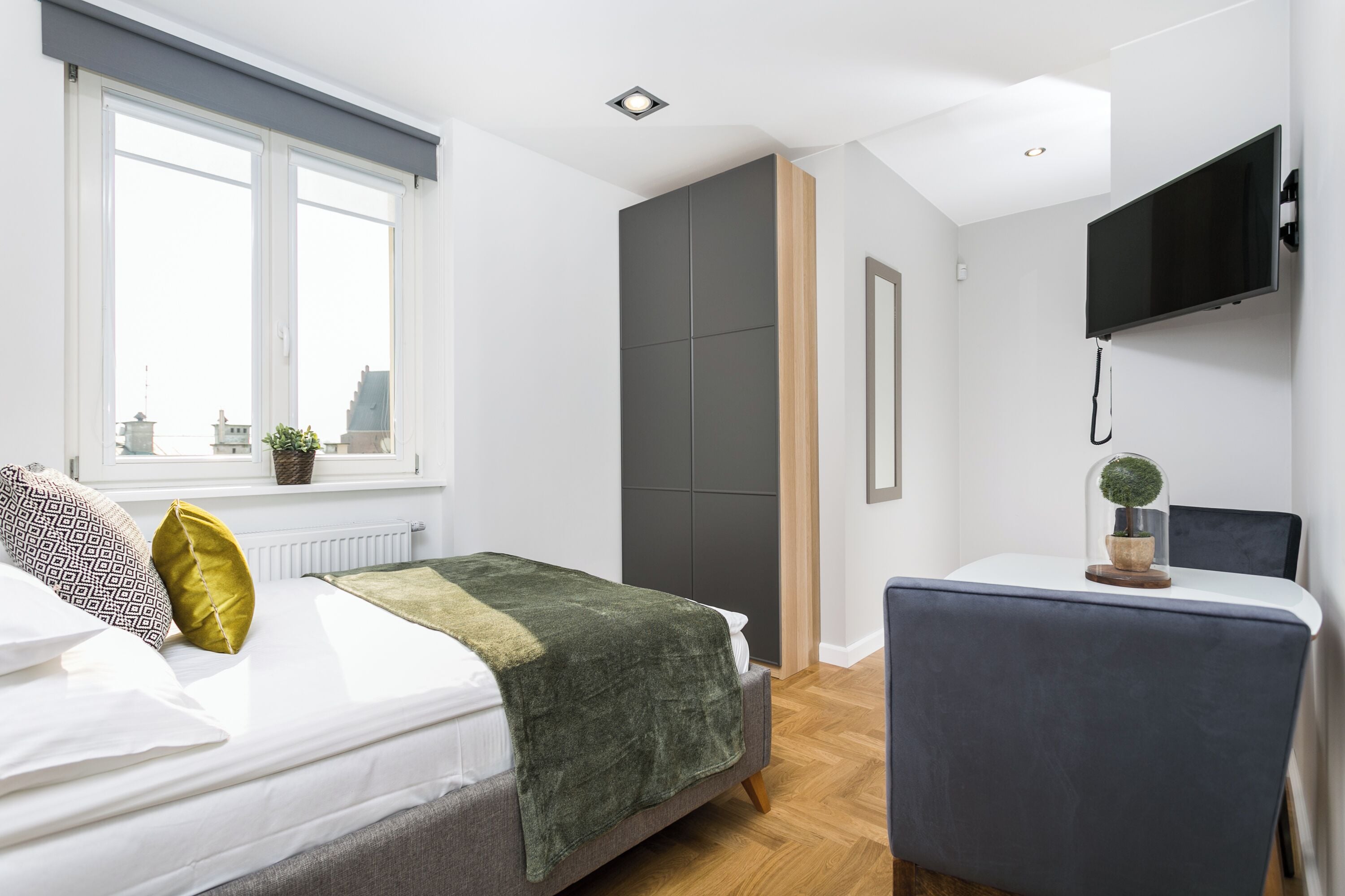 Une chambre à coucher moderne avec un lit, une table de chevet et un téléviseur fixé au mur.