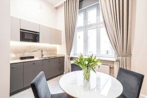 Una cucina moderna con forno a microonde integrato, lavandino e tavolo da pranzo con sedie.