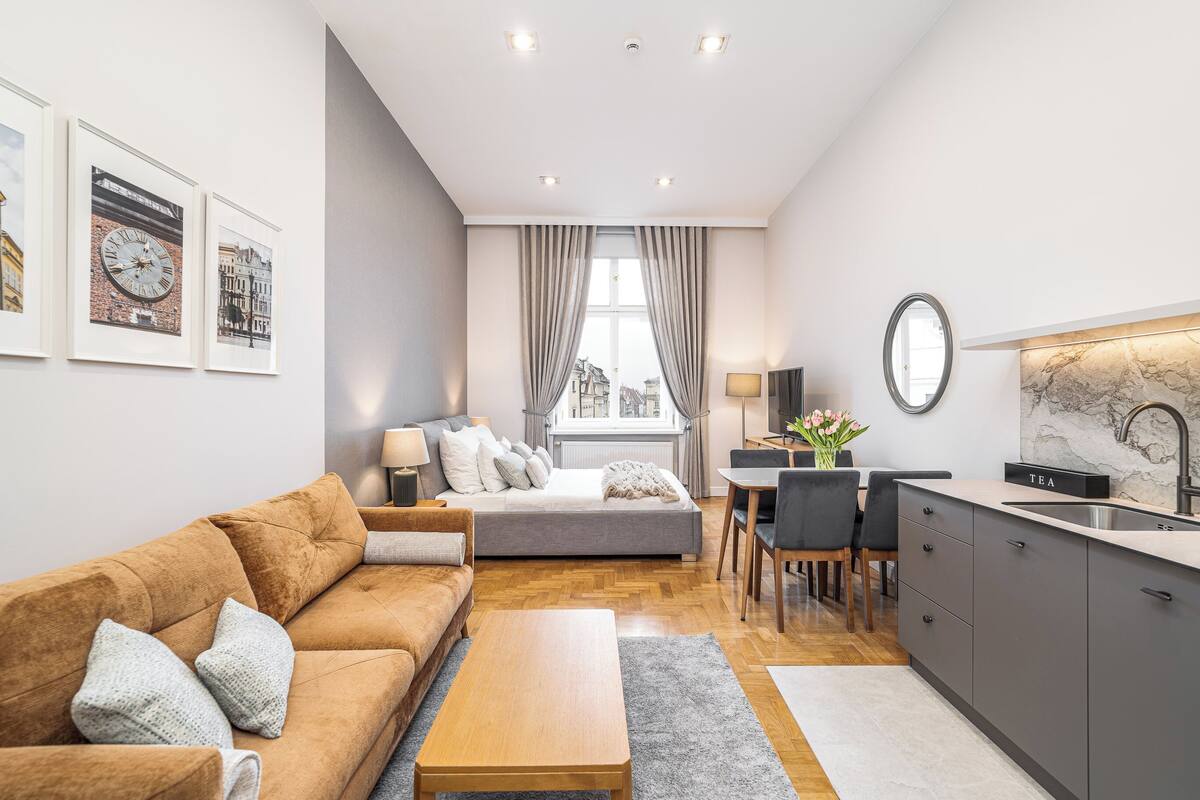 Un espacio habitable compacto con sofá, mesa de comedor, zona de cocina y cama.