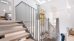 Un intérieur moderne avec un escalier en bois, une porte vitrée donnant sur un espace de vie et des fenêtres de toit.