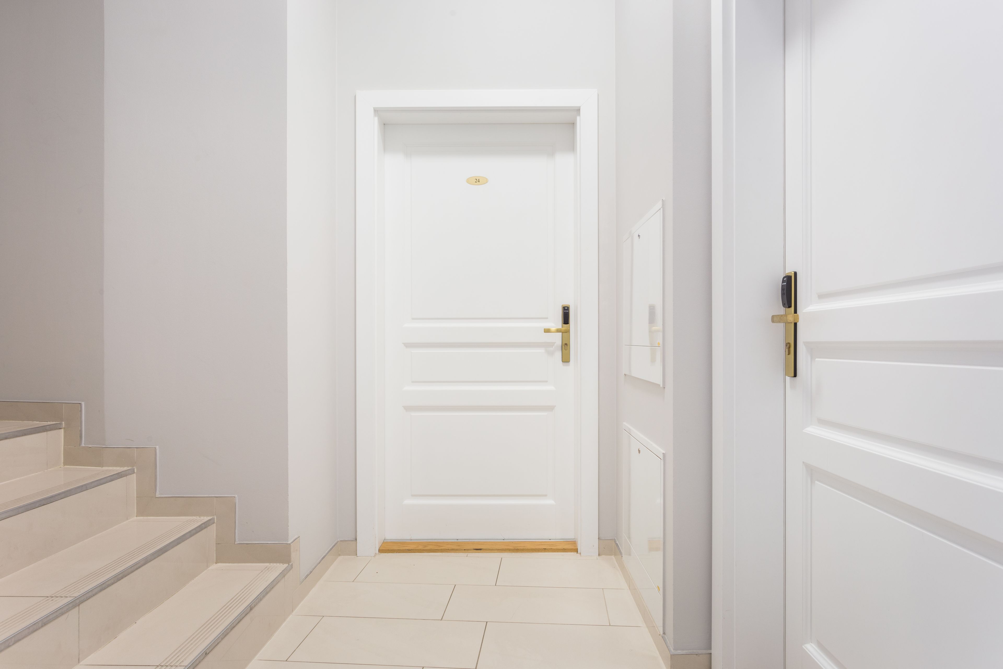 Une porte blanche avec une poignée en laiton et une petite plaque fixée au-dessus.