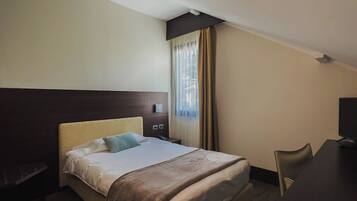 A hotel room with a bed, a desk, and a chair.
