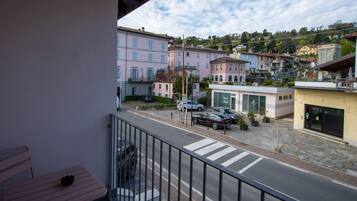 A balcony with a view of a street lined with buildings, a crosswalk, and parked cars.