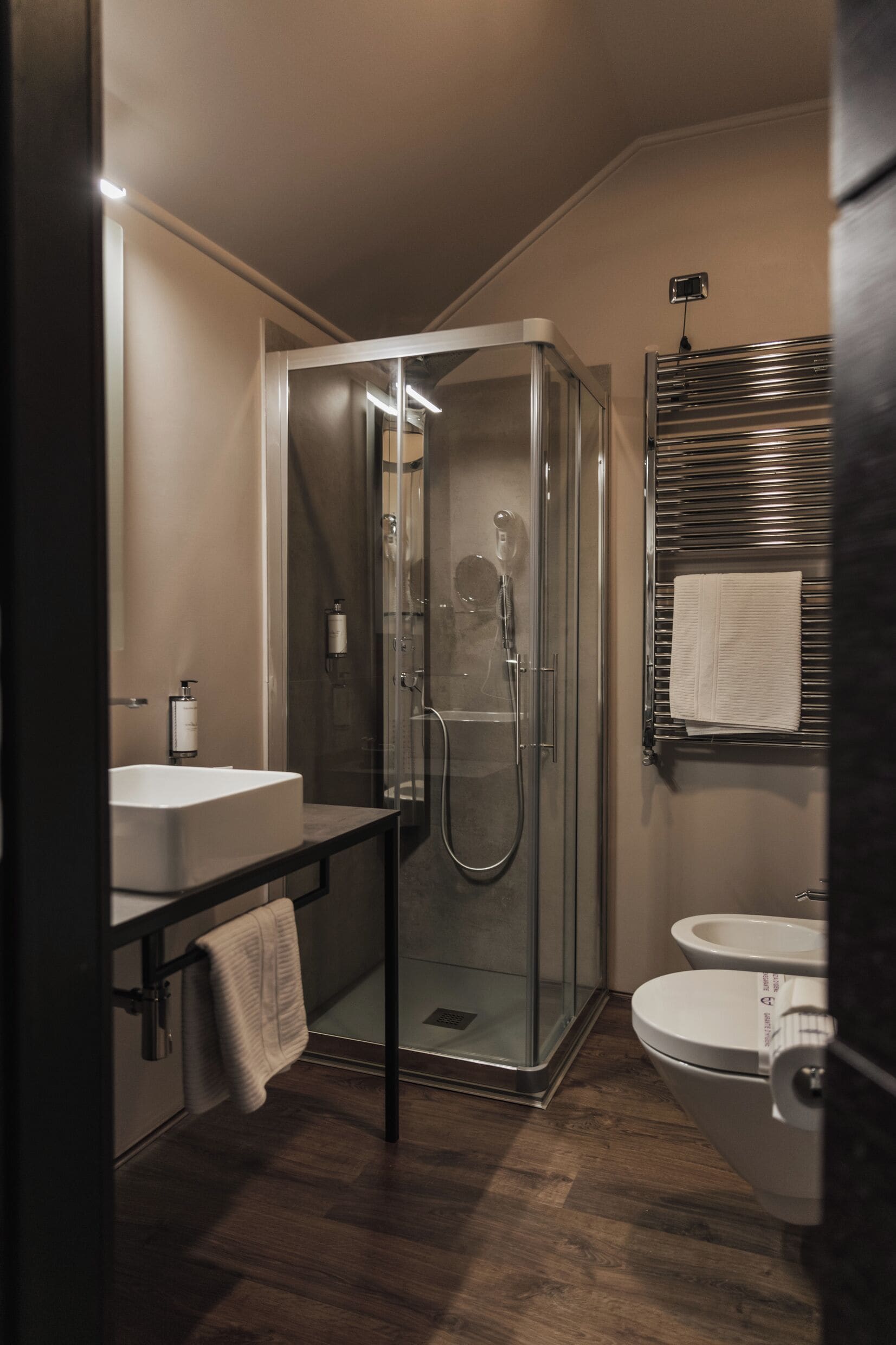 A modern bathroom with a glass-enclosed shower, a sink, and a toilet.