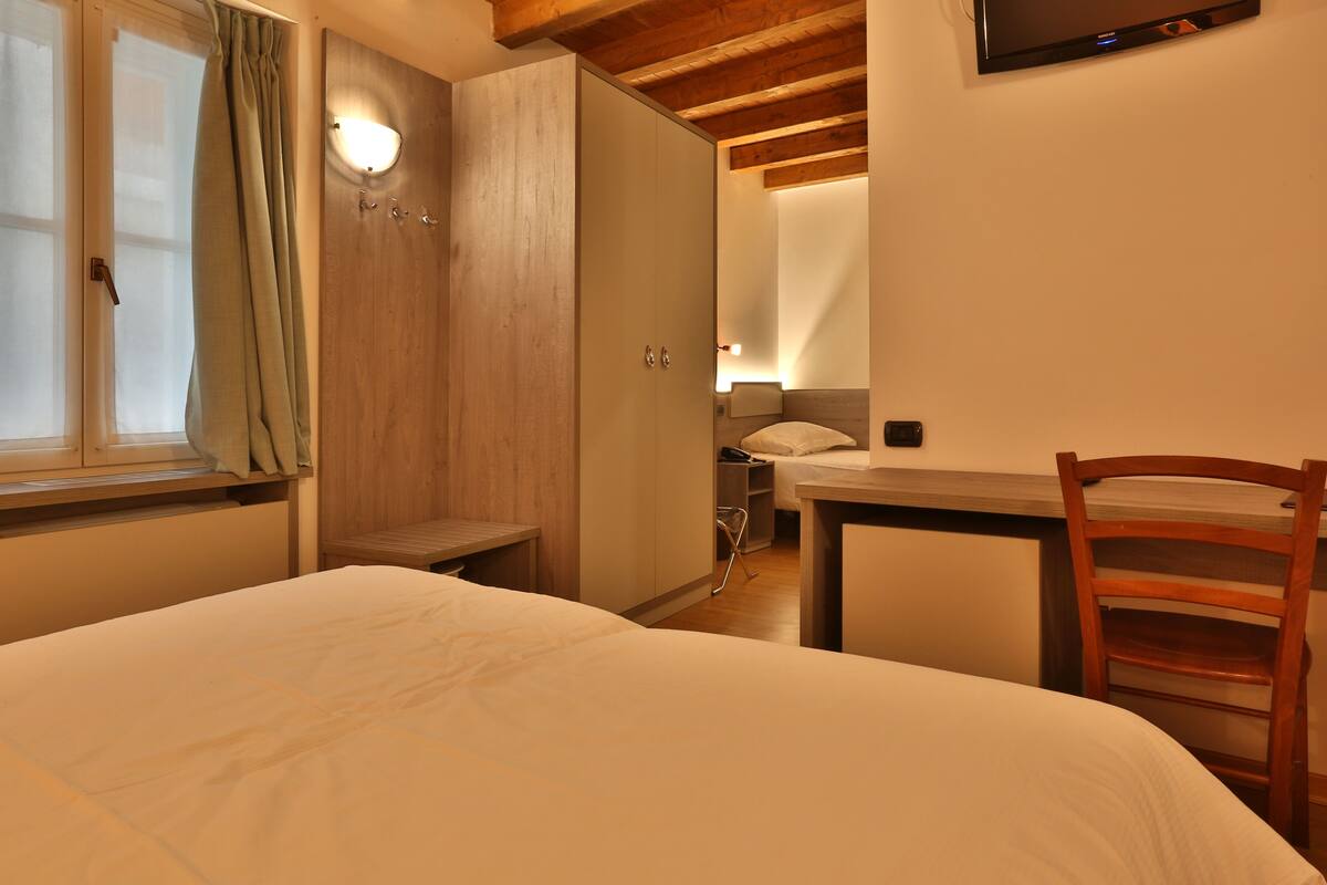 Ein Schlafzimmer mit Bett, Schreibtisch und Kleiderschrank.