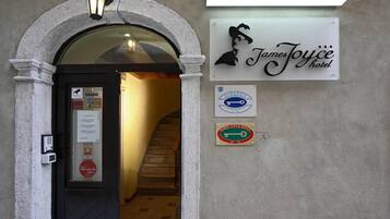 Entrada de un hotel con un cartel que indica Hotel James Joyce, un símbolo clave, y una etiqueta de la Guía Michelin.