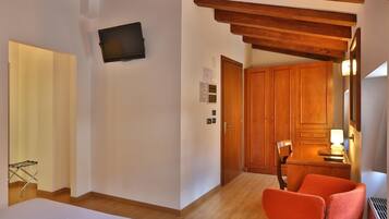 Quarto de hotel com cama, teto de madeira, TV fixada na parede e guarda-roupa de madeira.