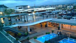 A multi-level outdoor pool area with a modern design, including a central pool, surrounding greenery, and a covered seating area. - ALU Hotel Davao (Davao)