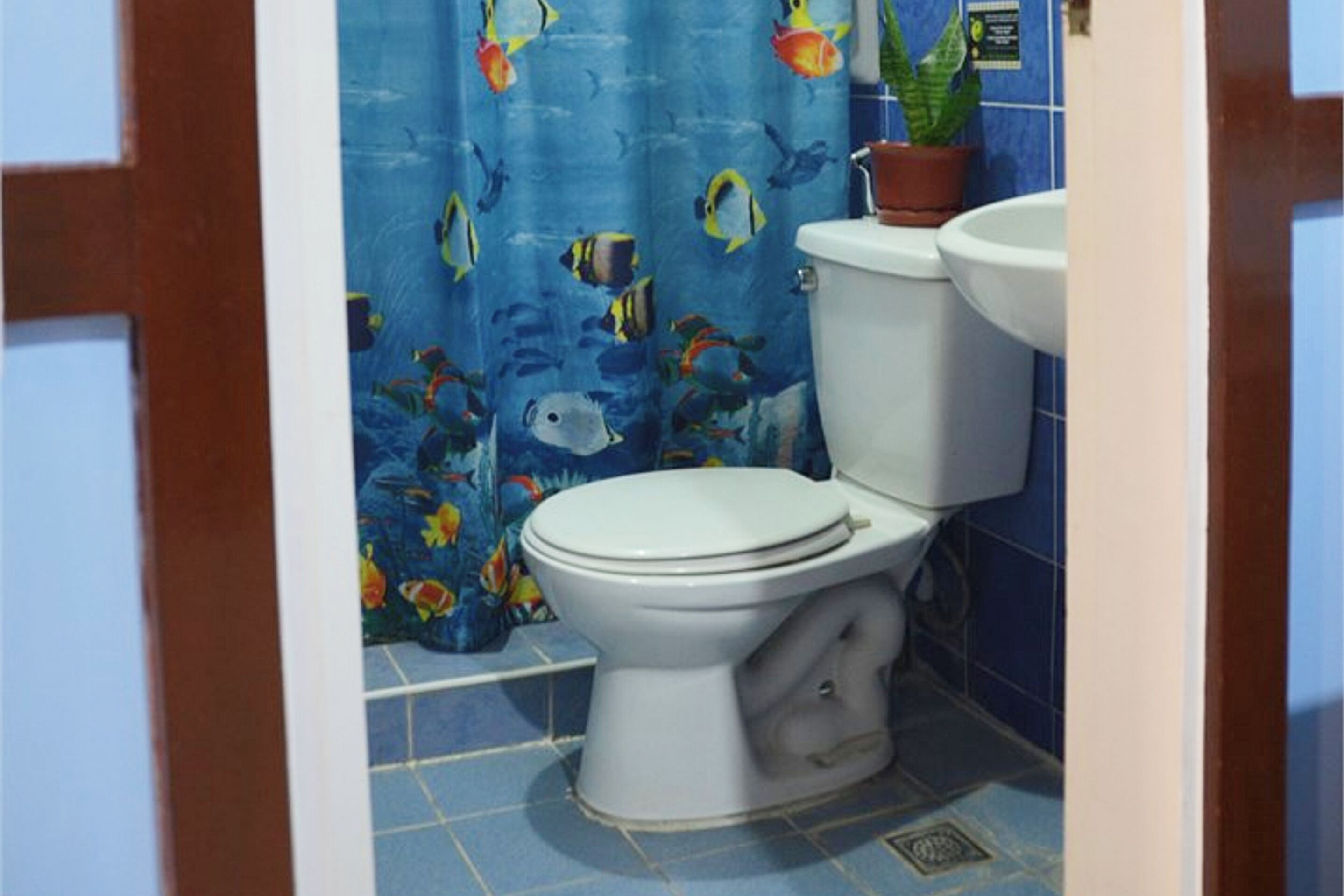 Un baño con inodoro, lavabo y cortina de ducha con estampado de peces.