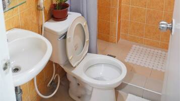 Ein Badezimmer mit Toilette, Waschbecken und Duschbereich.