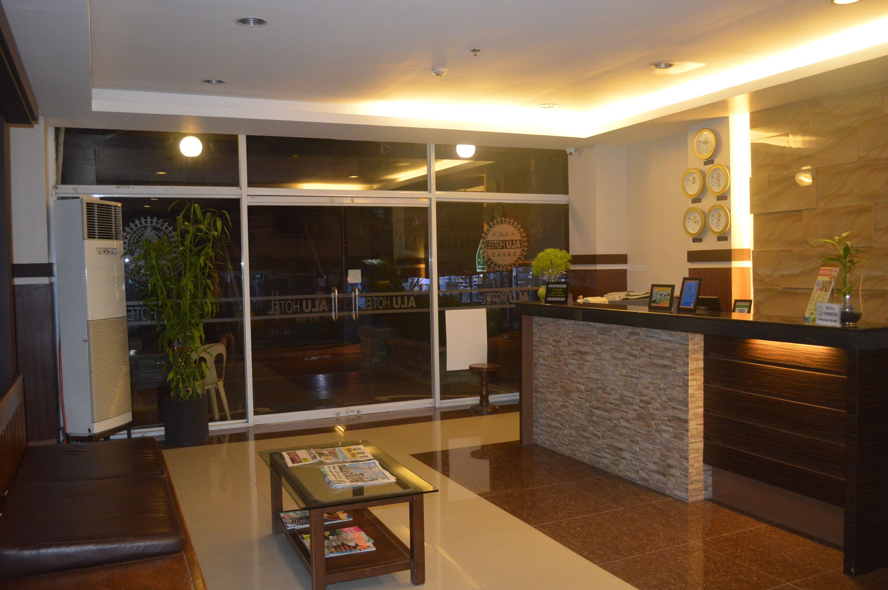 A hotel reception area with a modern design, featuring a reception desk, seating area, and large windows.