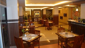 A hotel lobby with multiple dining tables and chairs, a reception desk, and a staircase leading to an upper floor. - ALU Hotel Davao (Davao)