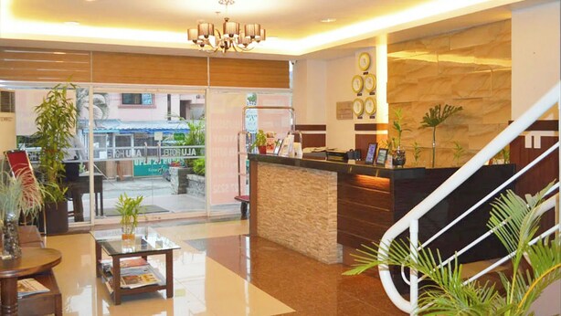 A hotel lobby with a reception desk, a staircase, and a view of the outside. - ALU Hotel Davao (Davao)