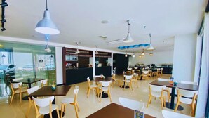A modern restaurant with multiple tables and chairs, a counter area, and pendant lighting. - Oceania Hotel (Kota Kinabalu)