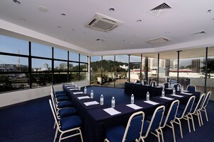 Une salle de conférence avec une longue table, des chaises et des bouteilles d’eau.