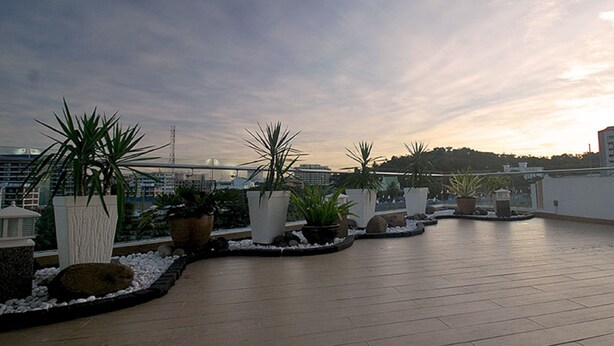 A rooftop terrace with potted plants and a view of the city skyline. - Oceania Hotel (Kota Kinabalu)