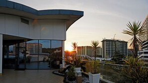A modern hotel with a curved exterior, large windows, and a rooftop garden with plants and a small water feature. - Oceania Hotel (Kota Kinabalu)