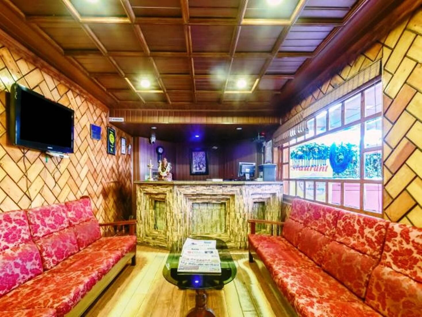 Una habitación con techo de madera, una mesa de recepción, un televisor y un sofá.