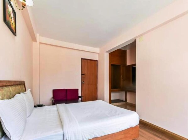 Un dormitorio con cama, una silla, un armario y una puerta.