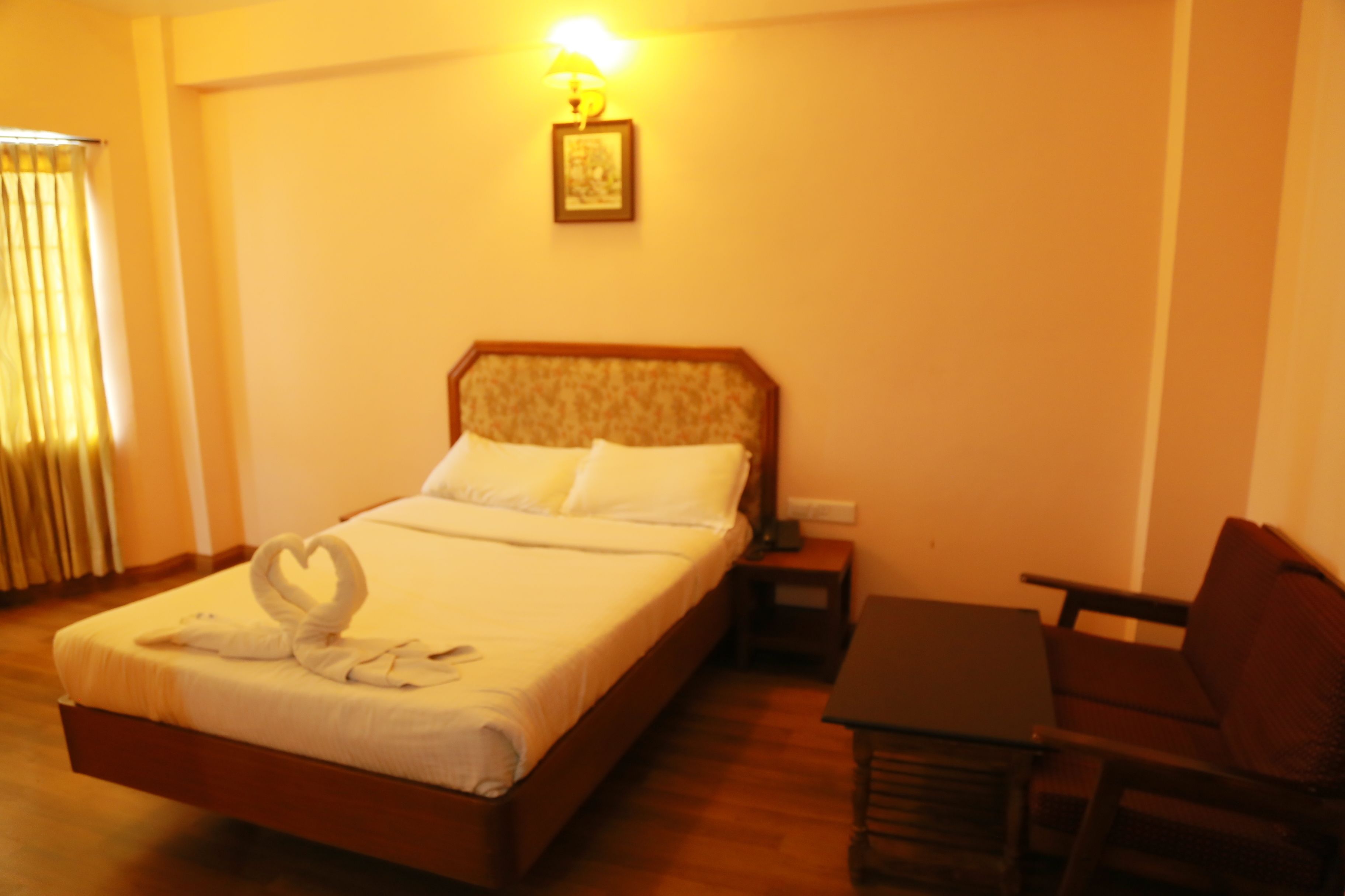 A hotel room with a bed, bedside table, and a chair.