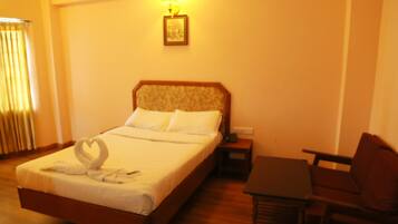 A hotel room with a bed, bedside table, and a chair.