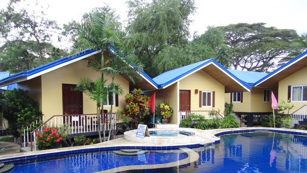 A pool area with a blue tiled floor, surrounded by two-story buildings with blue roofs and white railings. - Blue Lagoon Inn & Suites (Puerto Princesa)