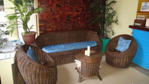 A wicker sofa with a blue cushion, a small round table with a candle, and a potted plant. - Blue Lagoon Inn & Suites (Puerto Princesa)
