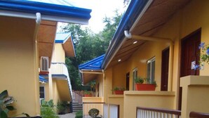 A narrow pathway flanked by yellow buildings with blue roofs, white railings, and potted plants. - Blue Lagoon Inn & Suites (Puerto Princesa)