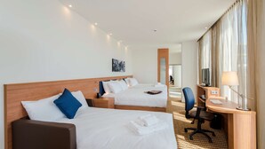 A hotel room with two beds, a desk, a chair, a TV, and a lamp. - Hampton by Hilton Amsterdam / Arena Boulevard (Amsterdam)