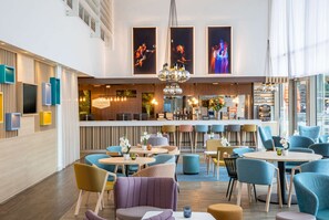 Um hall de hotel moderno com área de bar, assentos e obras de arte nas paredes.