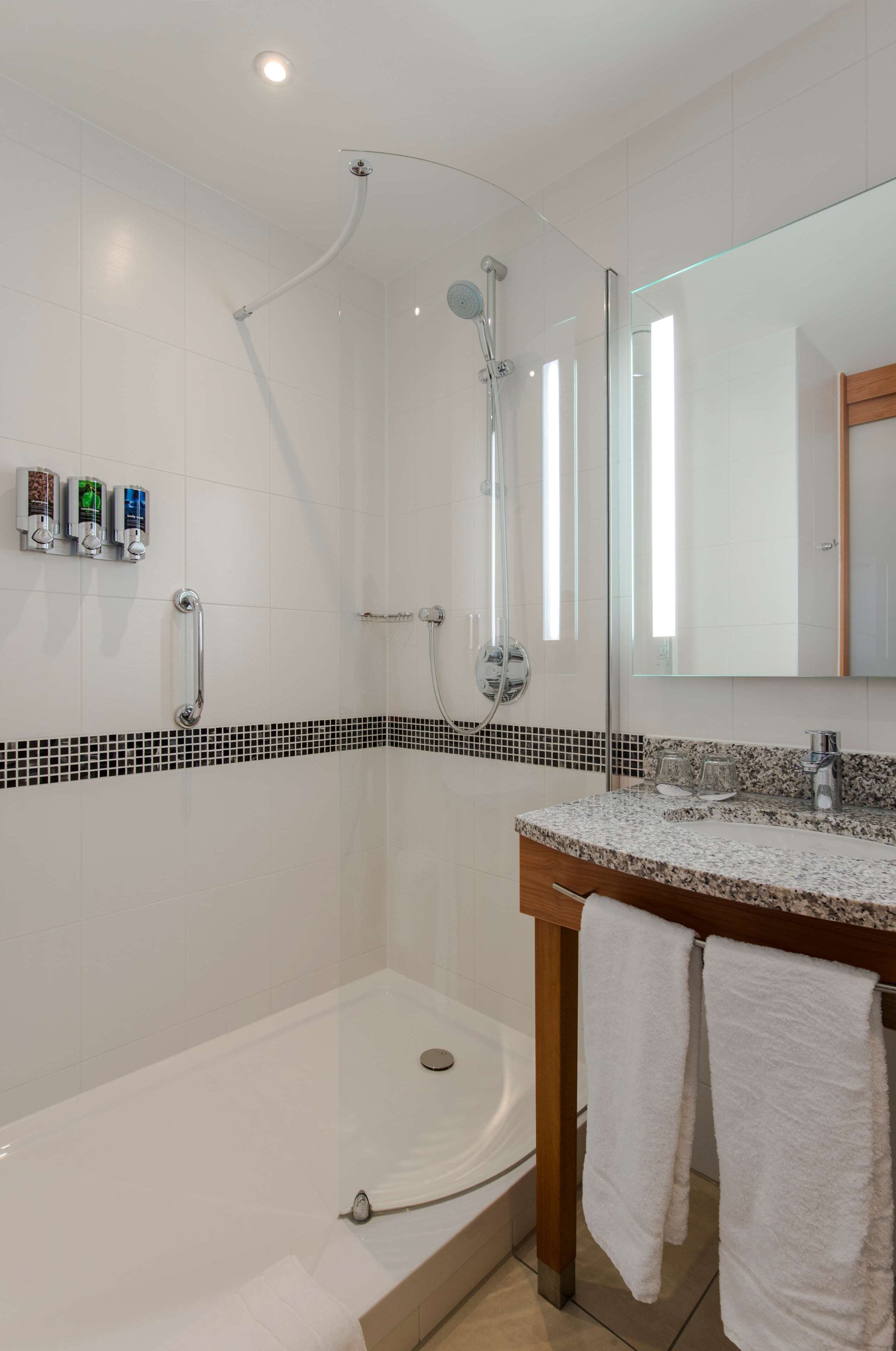 A modern bathroom with a glass-enclosed shower, a bathtub, and a vanity with a mirror.