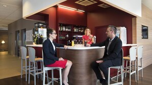 Un área de bar moderna con una barra curva, taburetes blancos y una pared roja de acento.