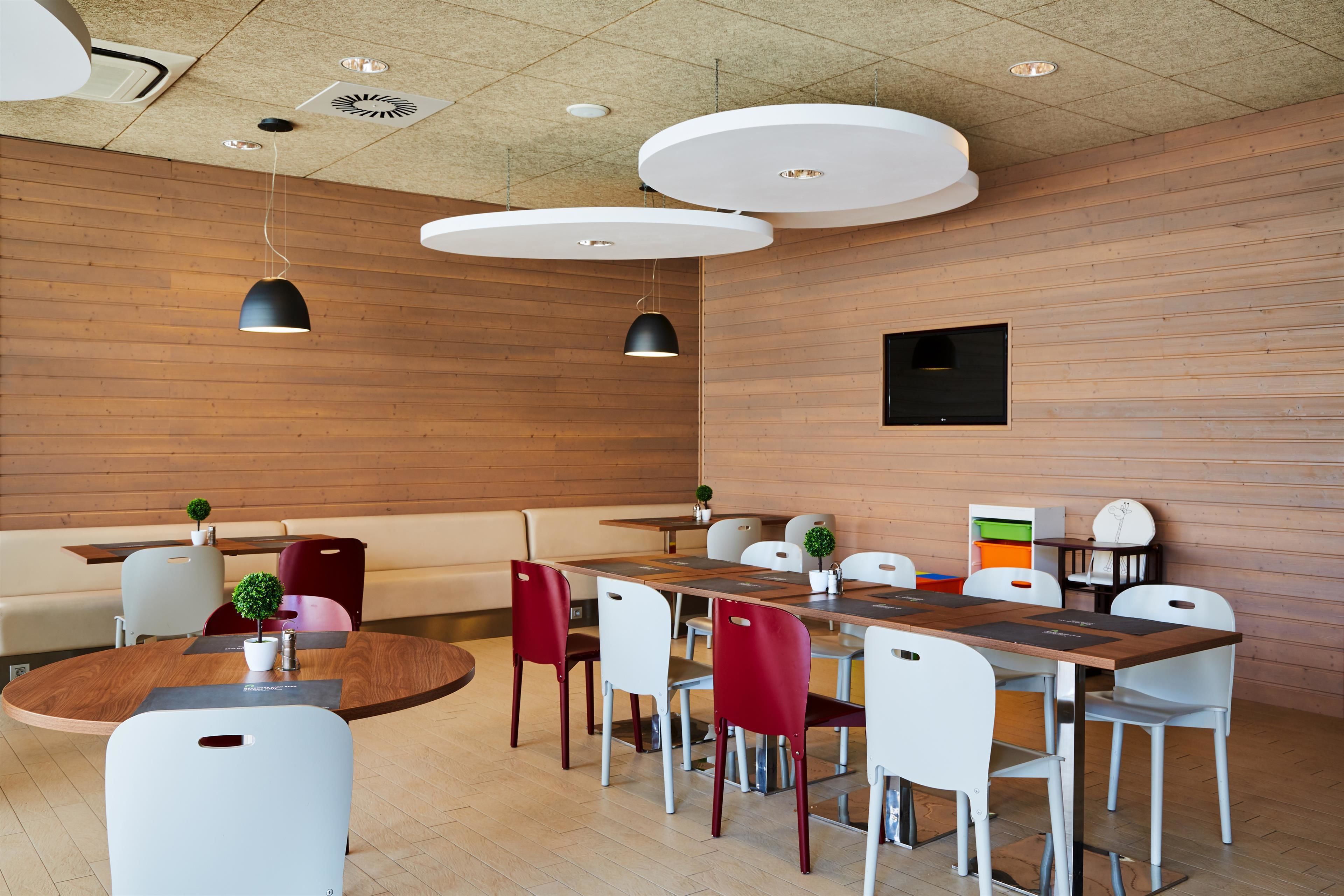 A modern conference room with wooden panel walls, a round table with chairs, and pendant lighting.