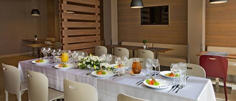 A dining area with a long table set for a meal, surrounded by chairs.