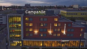 Un moderno edificio de hotel con fachada de vidrio, varios pisos y un letrero de restaurante.