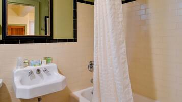A bathroom with a sink, mirror, and bathtub.