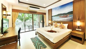 A bedroom with a large bed, a desk, and a view of the beach through the balcony.