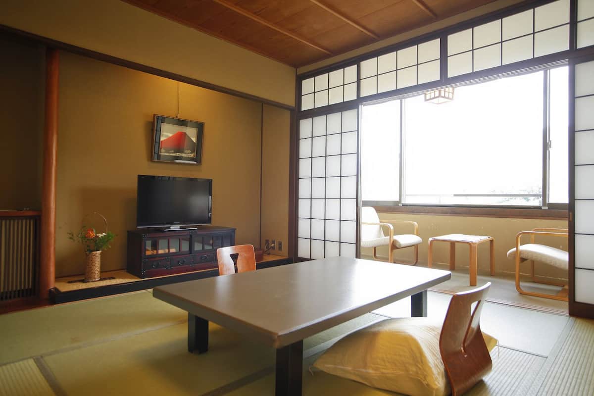 Habitació japonesa tradicional amb fons de tatami, una taula baixa, televisió i portes corredisses.