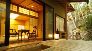 A traditional Japanese room with tatami flooring, a low table, and a chair.
