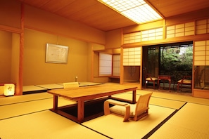 A traditional Japanese room with tatami flooring, a wooden table, and sliding doors leading to an outdoor area.